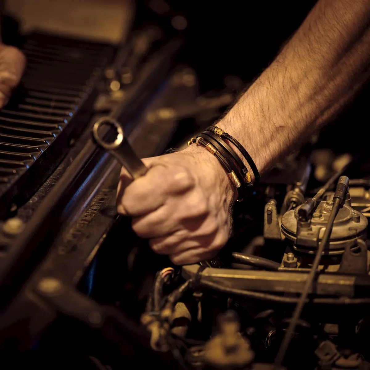 A mechanic's hand turning a wrench on a car engine